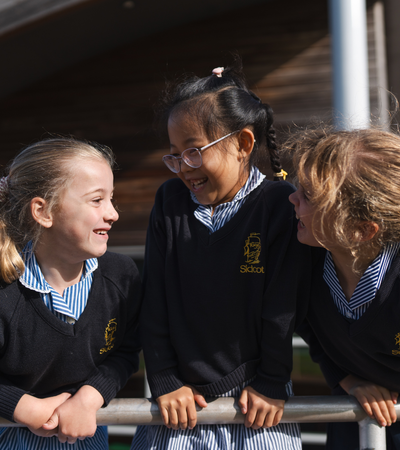 Three girls smiling outside Sidcot Junior School.