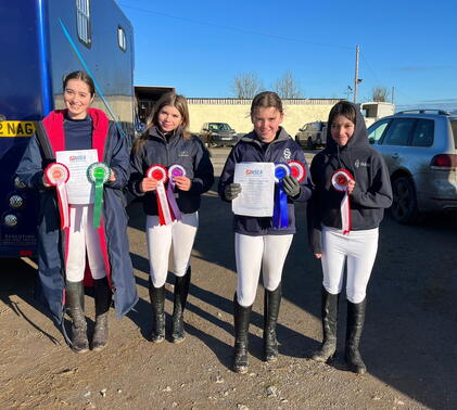 Equestrian team holding rosettes