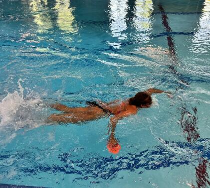 student swimming in pool attached to bungee rope