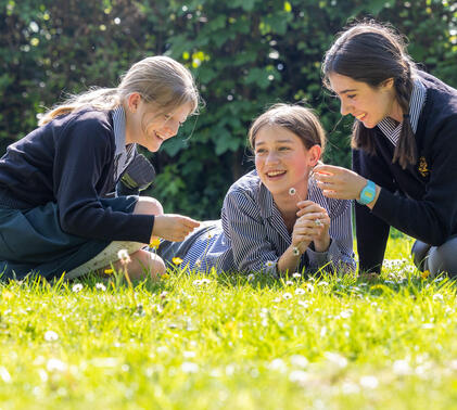 Sidcot Junior School pupils smiling as they lie down in the gardens