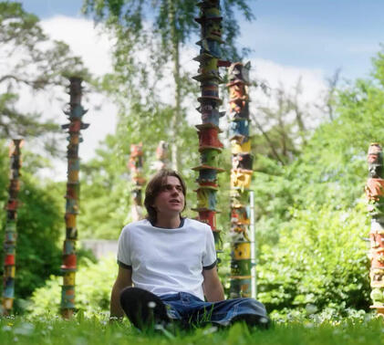 Sidcot student smiling outside in front of clay totem poles