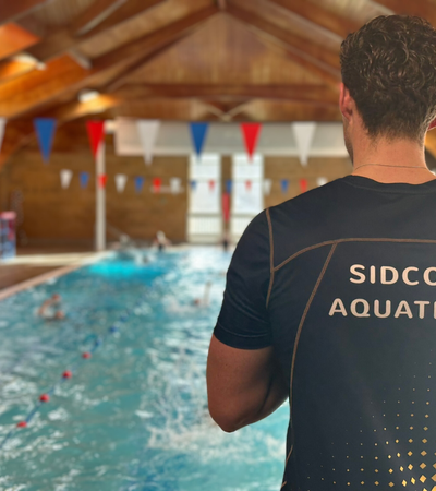 A swimming teacher looking over a pool.