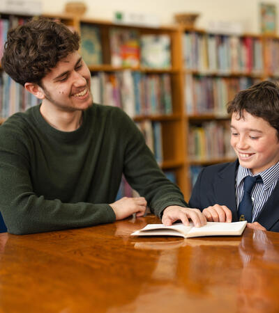 Sidcot Sixth Form student reading with Year 7 student