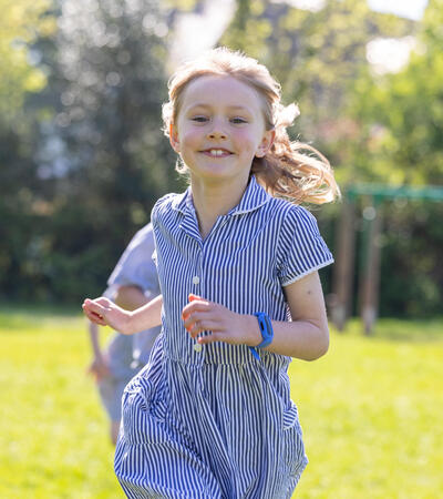 Sidcot Junior School pupil running outside and smiling