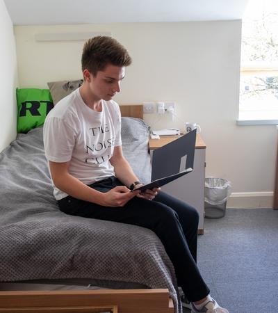 boy at boarding school sat on bed